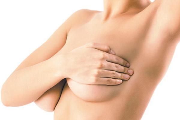 Close up of a mother’s midsection after breast lift surgery, her nipples concealed by her hands