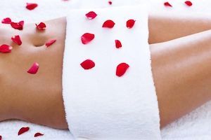 woman lying down with towel covering waist and rose petals